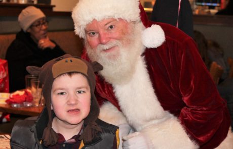 Child posing with Santa Claus during a festive event.