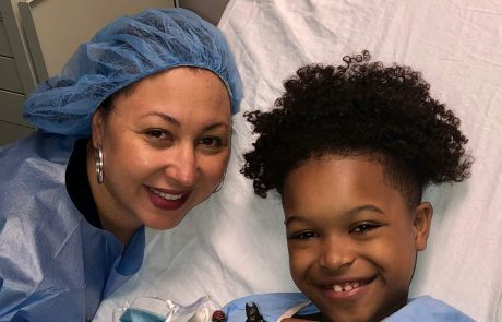 A joyful child and nurse in hospital gowns sharing a happy moment.