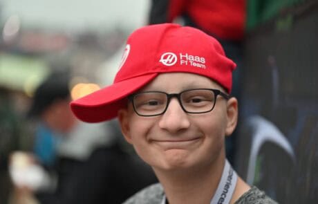 Smiling young person wearing glasses and a red cap.