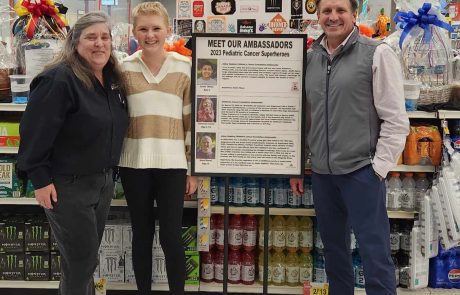 Four people posing in a store aisle with shelves of products behind them.