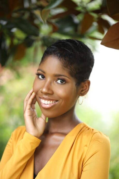 A smiling woman with short hair wearing a yellow top.