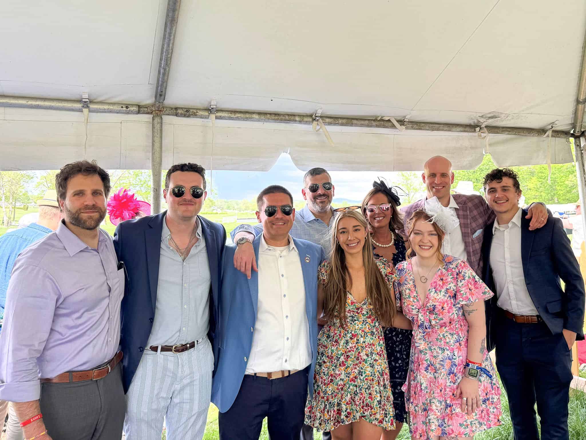 Group of friends dressed stylishly at an outdoor event under a tent.