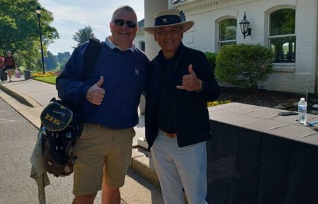 Two men posing together outdoors, both giving thumbs up.