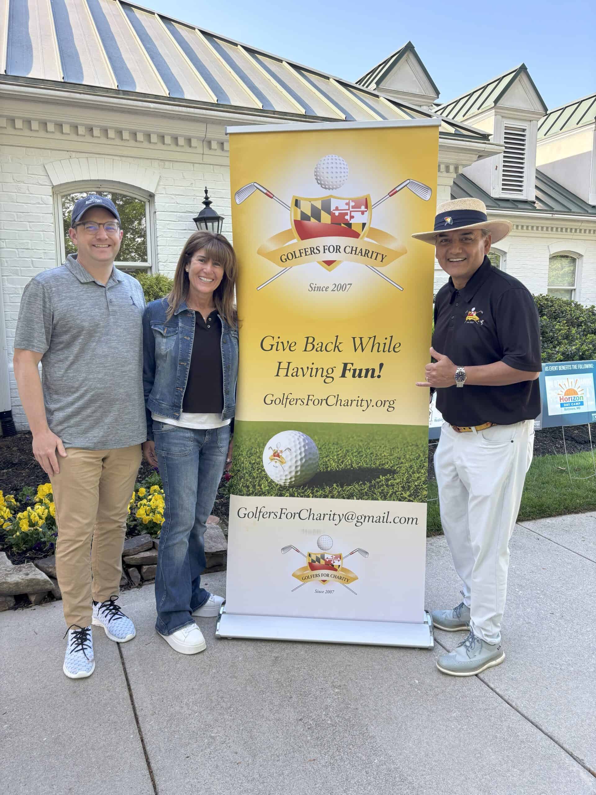Three people standing outdoors with a banner promoting honey food.