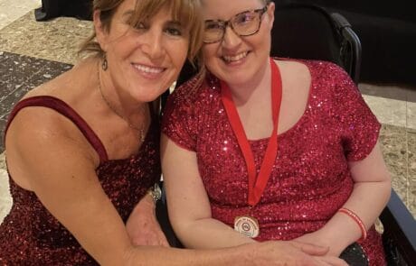 Two women smiling warmly, one in a wheelchair.