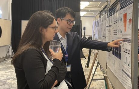 Two professionals discuss research findings at a conference poster session.