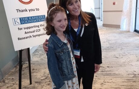 Two women posing together at a conference venue near a sign.